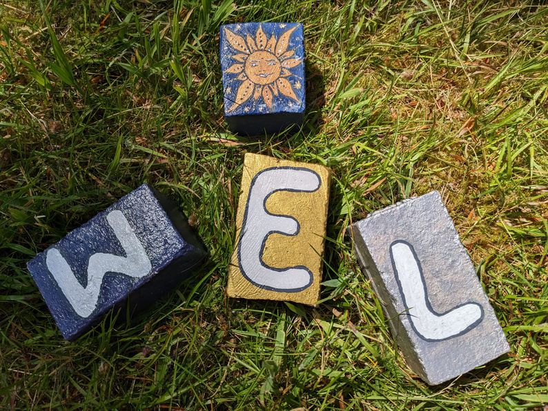 Three painted bricks adorned with the letters 'W', 'E', and 'L'