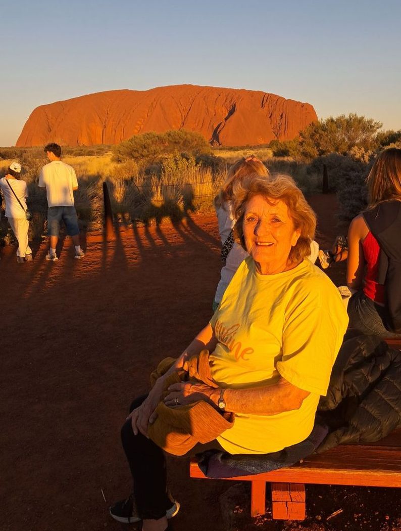 Woman in foreground with Uluru in the background